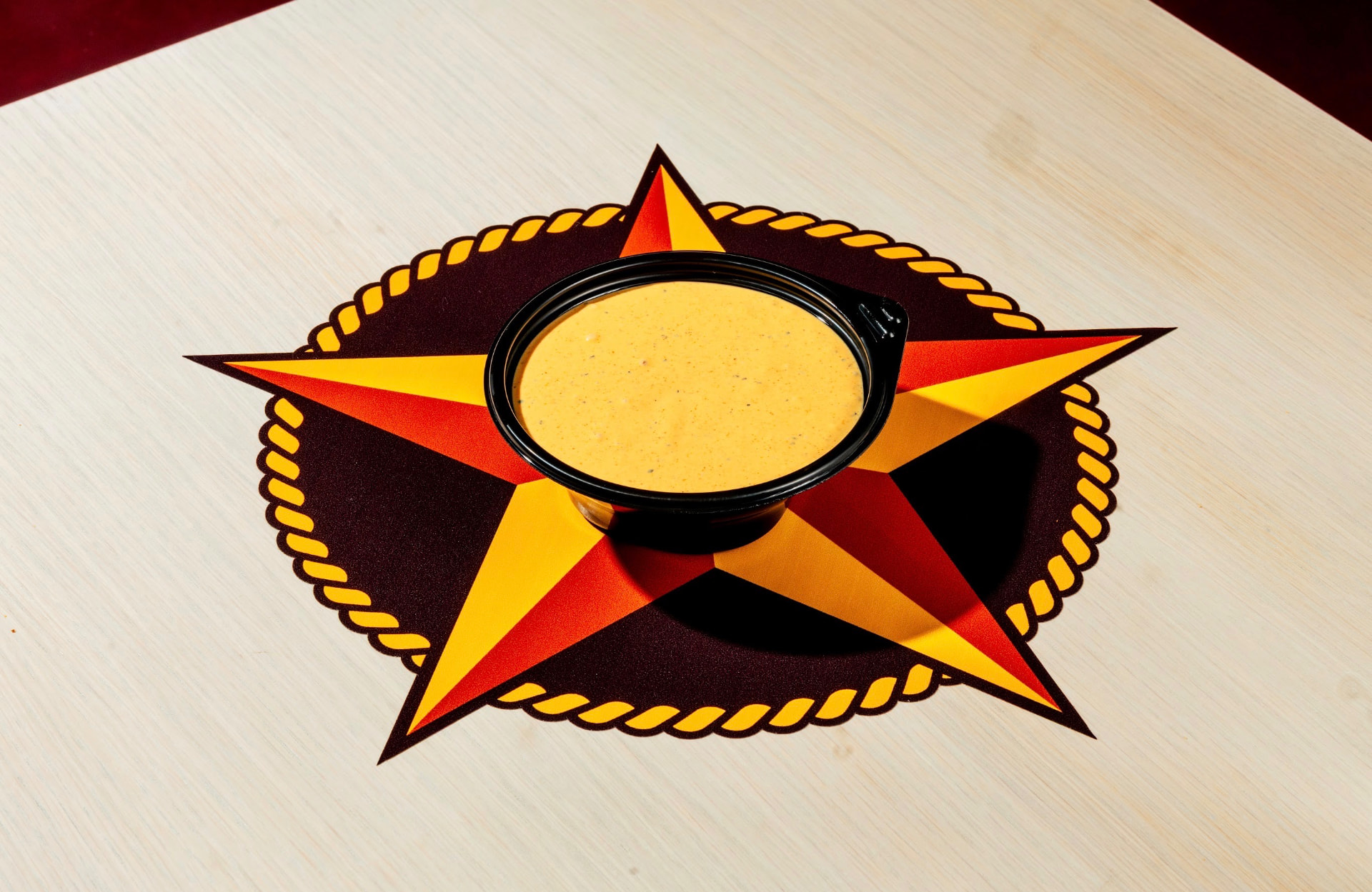 Cup of Hotbirds comeback sauce on a star placemat